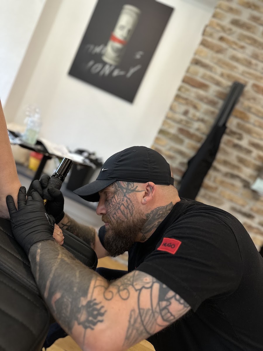 Tätowierer bei der Arbeit an einem Kundenarm, StudioNo83